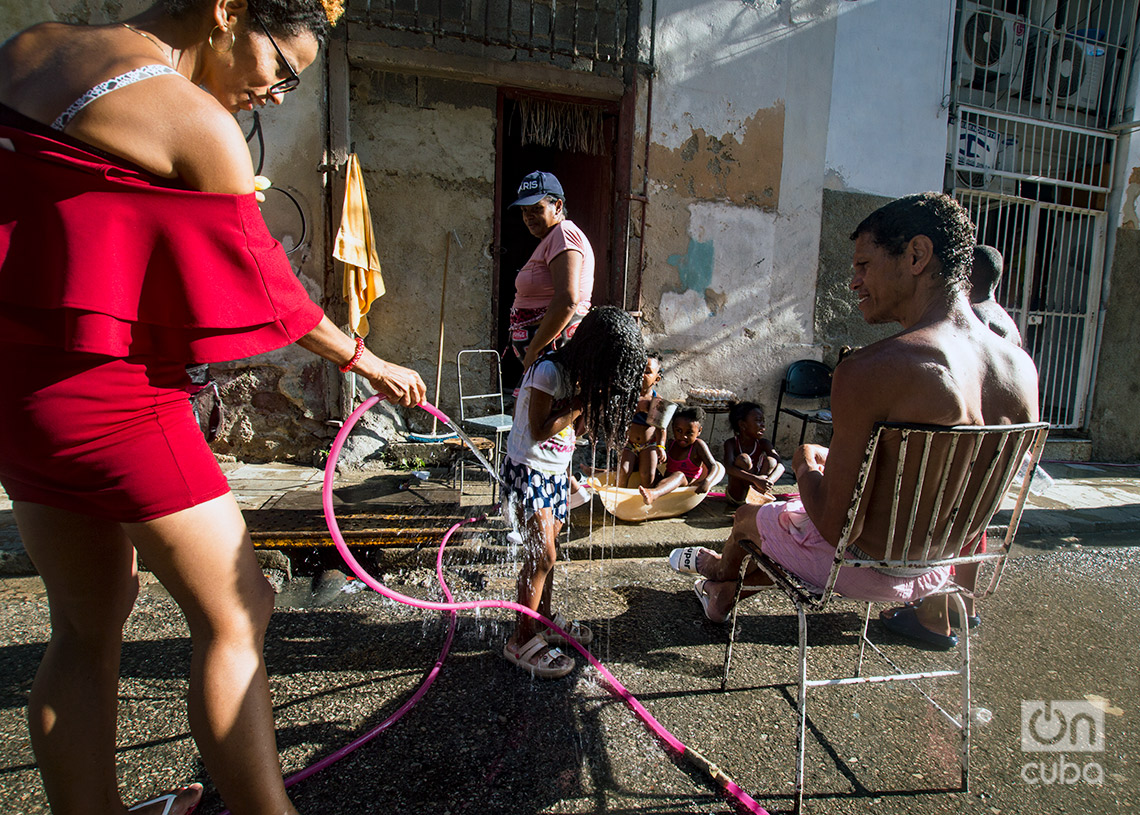 Familia refrescándose con agua suministrada por una manguera en una calle de La Habana en el verano de 2024. Foto: Otmaro Rodríguez.